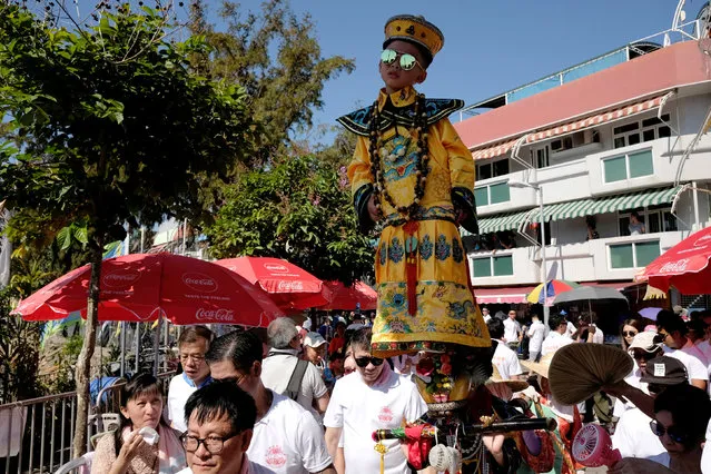 A child, standing above the crowd with the support of an elaborate rig of hidden metal rods, takes part in the Bun Festival parade at Cheung Chau island in Hong Kong, China May 22, 2018. Thousands of local residents and tourists flocked to an outlying island in Hong Kong to celebrate a local bun festival on Tuesday despite the recording-breaking heat.  The festival features a parade with children dressed as deities floated on poles. Later on Tuesday, contestants will take part in bun-scrambling competition. They will race up a 14-meter bamboo tower to snatch as many plastics buns as possible. Buns that are higher up are worth more points. (Photo by Bobby Yip/Reuters)