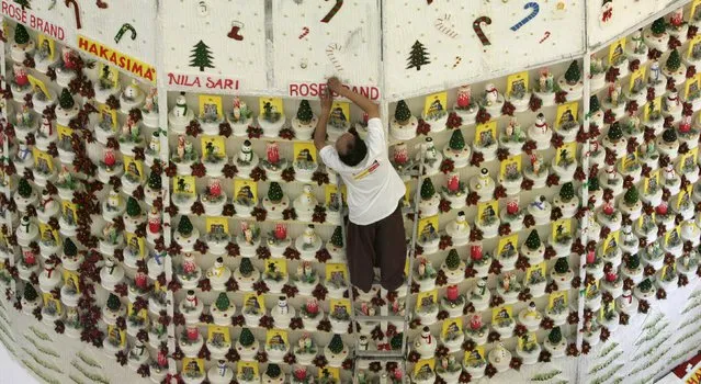 A worker puts the final touch to a 33-metre tall mock Christmas tree decorated with hundreds of cakes in a Jakarta shopping mall in this November 28, 2008 file photo. Indonesia is expected to release inflation numbers this week. (Photo by Reuters/Supri)