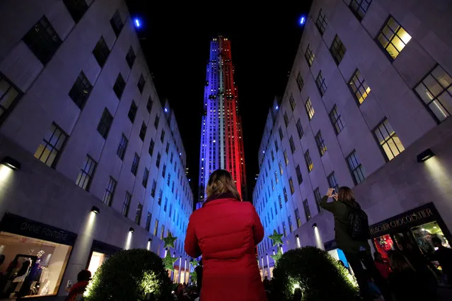 People take pictures of 30 Rockefeller Plaza as it is lit in the colors of the Democratic and Republican parties ahead of the U.S presidential election in Manhattan, New York, U.S., November 7, 2016. (Photo by Andrew Kelly/Reuters)