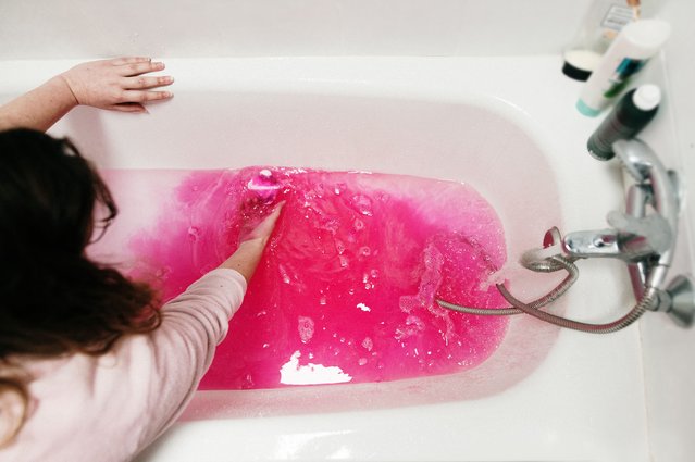 A woman putting a pink bath bomb in the water in a bathtub. (Photo by Mario Guti/Getty Images)