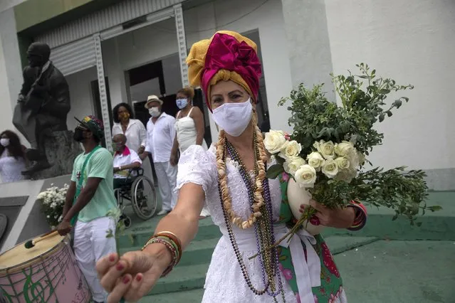 A samba school member offers herbs during a ceremony marking the symbolic start of Carnival at the Samba Museum during the COVID-19 pandemic in Rio de Janeiro, Brazil, Friday, February 12, 2021. The school performed a cleansing ceremony at a time that normally would be the start of four days of parades and parties, but this year Carnival will mostly take place online after city officials canceled festivities due to the pandemic. (Photo by Silvia Izquierdo/AP Photo)