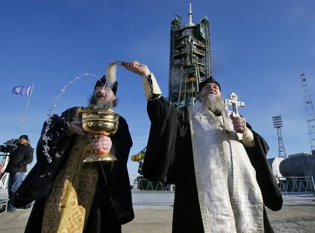 Orthodox priests conduct a blessing service in front of the Soyuz TMA-19M spacecraft at Russian leased Baikonur cosmodrome, Kazakhstan, Monday, December 14, 2015. The new Soyuz mission is scheduled to start on Tuesday, December 15. The Russian rocket will carry U.S. astronaut Tim Kopra, Russian cosmonaut Yuri Malenchenko and British astronaut Tim Peake. (Photo by Dmitry Lovetsky/AP Photo)