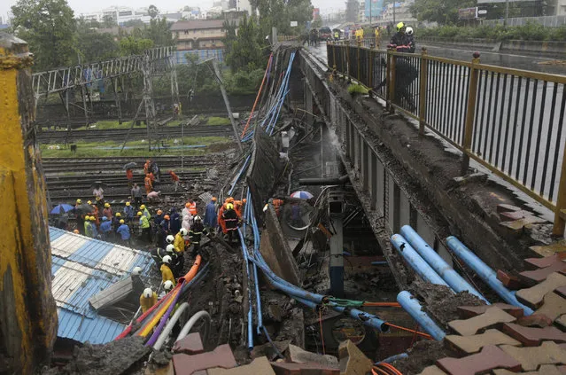 Rescuers work at the site of a pedestrian bridge that collapsed at a train station in Mumbai, India, Tuesday, July 3, 2018. Part of a pedestrian bridge at a Mumbai train station collapsed Tuesday morning during heavy rains. The concrete slab fell onto empty train tracks, damaging part of the platform roof and high-tension electric wires. (Photo by Rafiq Maqbool/AP Photo)
