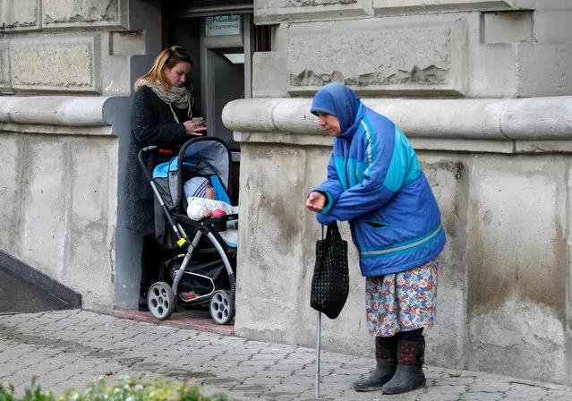 A woman uses an ATM as an elderly woman begs for money in central Chisinau, Moldova, November 12, 2016. (Photo by Gleb Garanich/Reuters)