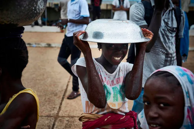 A girl poses with a metal bowl over her head on the sidelines of a protest against the incumbent Malian president in Bamako on August 11, 2018, on the eve of the second round of presidential elections in Mali. (Photo by Michele Cattani/AFP Photo)