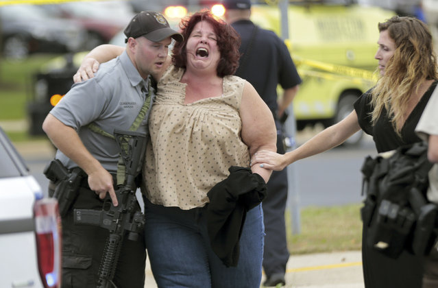 A woman is escorted from the scene of a shooting at a software company in Middleton, Wis., Wednesday, September 19, 2018. Four people were shot and wounded during the shooting in the suburb of Madison, according to a city administrator. (Photo by Steve Apps/Wisconsin State Journal via AP Photo)