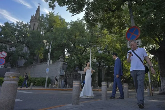 People walk by a newly weds preparing for their wedding photos taken near the Dongjiaominxiang Catholic Church in Beijing, Friday, September 1, 2023. Pope Francis arrived in Mongolia on Friday morning on a visit to encourage one of the world’s smallest and newest Catholic communities. (Photo by Andy Wong/AP Photo)