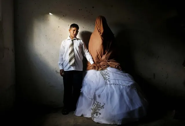 Ahmed Soboh, 15 and his bride Tala, 14, stand inside Tala's house which was damaged during an Israeli strike in 2009, during their wedding party in the town of Beit Lahiya, near the border between Israel and the northern Gaza Strip, on September 24, 2013. (Photo by Mohammed Salem/Reuters)