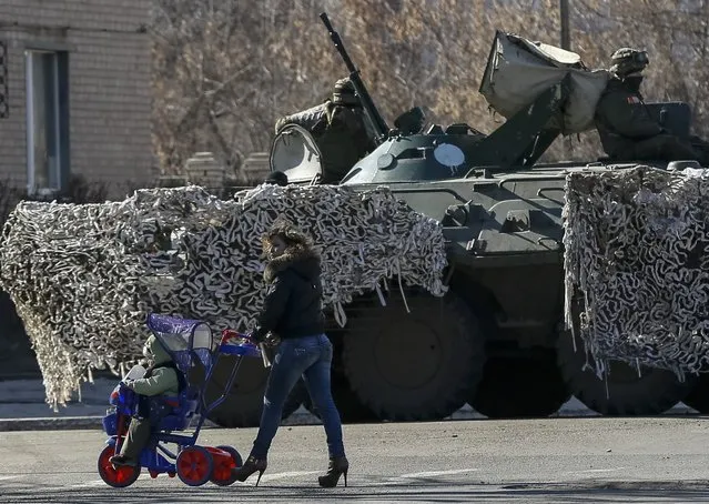 Local residents walk near an armoured personnel carrier of Ukrainian armed forces in Artemivsk, eastern Ukraine, February 21, 2015.  REUTERS/Gleb Garanich  (UKRAINE - Tags: POLITICS CIVIL UNREST MILITARY SOCIETY)