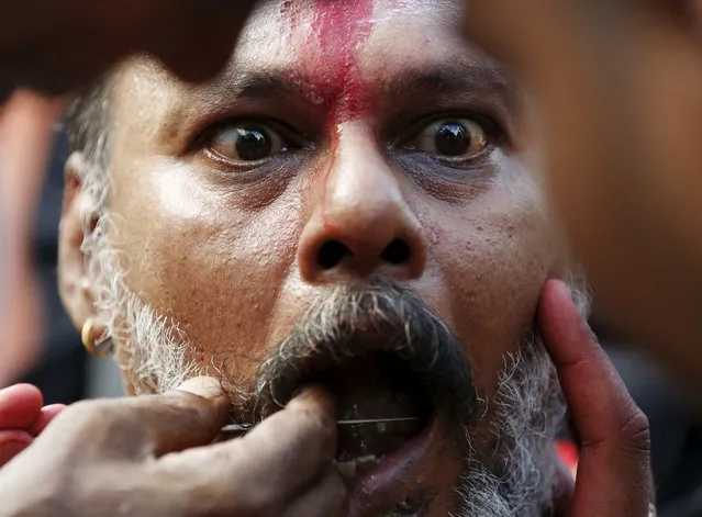 A Hindu devotee reacts as his cheeks are pierced during Thaipusam at Batu Caves in Kuala Lumpur, Malaysia, January 23, 2016. (Photo by Olivia Harris/Reuters)