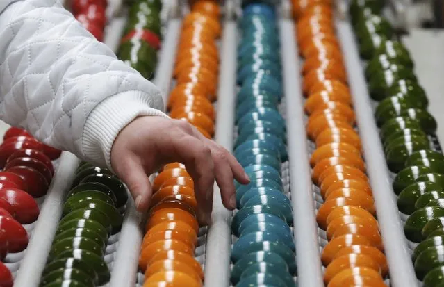 An employee sorts cooked and coloured eggs on a conveyor belt at the Schrall coloured eggs company in the Austrian Village of Diendorf March 16, 2015. (Photo by Leonhard Foeger/Reuters)
