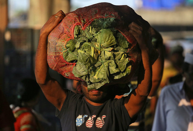 A man carries a sack filled with cabbage at a wholesale market in Mumbai, India, December 14, 2018. (Photo by Francis Mascarenhas/Reuters)