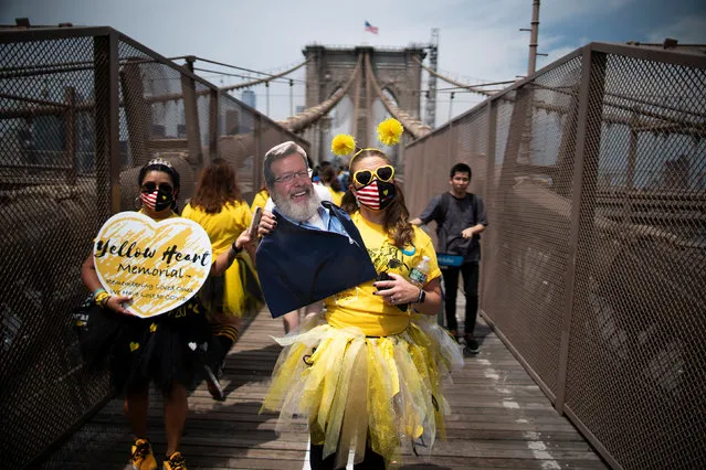 A woman carries a picture of his late father as they walk across the Brooklyn Bridge together for those who were lost due to coronavirus disease (COVID-19) in New York, U.S., August 7, 2021. (Photo by Eduardo Munoz/Reuters)