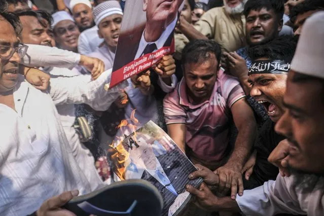 Muslims burn a portrait of Israeli Prime Minister Benjamin Netanyahu during a protest against Israel's military operations in Gaza and to support the Palestinian people, in front of Baitul Mukarram mosque in Dhaka, Bangladesh, Friday, October 13, 2023. (Photo by Mahmud Hossain Opu/AP Photo)