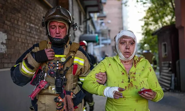 Fireman helps injured civilians after several explosions rocked the Shevchenkivskyi district of the Ukrainian capital, Kyiv on October 10, 2022. (Photo by Ukrainian State Emergency Service/Handout/Anadolu Agency via Getty Images)