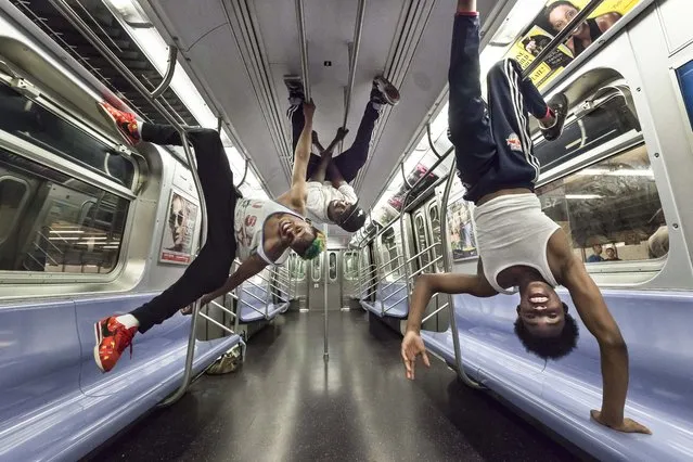 (L-R) Andrew “Goofy” Saunders, Dashawn Martin and Raymon “Lex” Santos perform dynamic dance moves while hanging upside-down from the handrails in a New York City subway car. (Photo by Wiktor Skupinski/Barcroft Media)