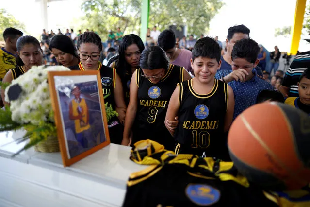 Basketball teammates gather around the coffin of Marco Pimentel, who was murdered by suspected gang members along with his mother and three other relatives of Omar Pimentel, a member of the coaching staff of first division soccer team Sonsonate, in Chalchuapa, El Salvador February 9, 2019. (Photo by Jose Cabezas/Reuters)