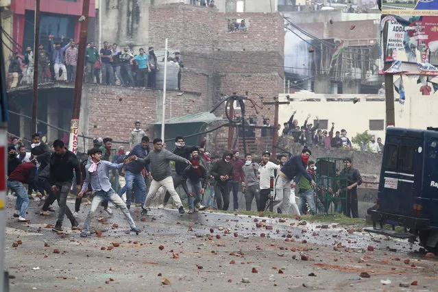 Protestors throw stones during a clash between communities while protesting against Thursday's attack on a paramilitary convoy that killed at least 40 in Kashmir, in Jammu, India, Friday, February 15, 2019. Prime Minister Narendra Modi placed the blame for Thursday's bombing squarely on neighboring Pakistan, which India accuses of supporting rebels in Kashmir. The attack has raised tensions elsewhere in Hindu-majority India. Hundreds of residents carrying India's national flag in Hindu-dominated Jammu city in the Muslim-majority state burned vehicles and hurled rocks at homes in Muslim neighborhoods, officials said. (Photo by Channi Anand/AP Photo)