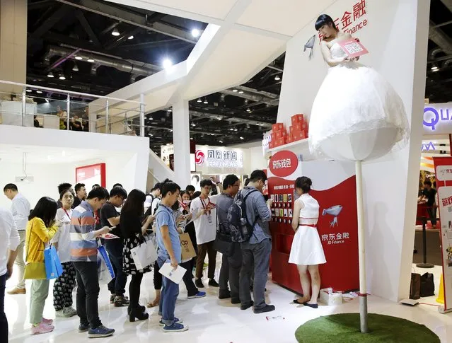 A promotional staff stands on a pole as part of an installation depicting a flower, at JD Finance's booth at the Global Mobile Internet Conference (GMIC) 2015 in Beijing, China, April 28, 2015. (Photo by Kim Kyung-Hoon/Reuters)