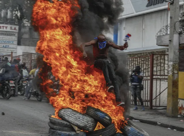 A protester jumps burning tires during a protest against Haitian Prime Minister Ariel Henry in Port-au-Prince, Haiti, Monday, February 5, 2024. (Photo by Odelyn Joseph/AP Photo)