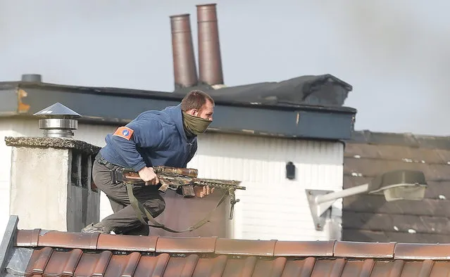 A police officer runs on top of a roof during a police operation on the site of a shooting in the rue du Dries in Forest-Vorst, Brussels, Belgium, 15 March 2016. A shooting took place during a police raid linked to the Paris terrorist attacks. According to reports, two members of federal police were injured in the operation and police were still searching for the shooter. (Photo by Laurent Dubrule/EPA)