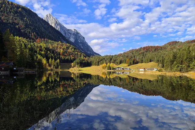 Clouds are reflected on a autumn colored lake near Mittenwald, Germany, Tuesday, October 26, 2021. (Photo by Daniel Boettcher/AP Photo)