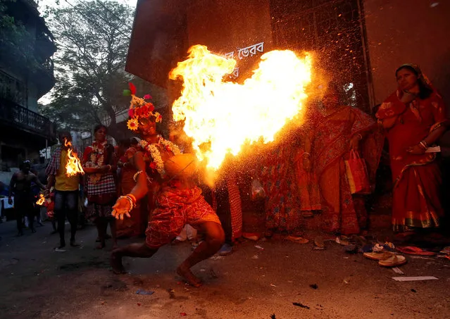 A man throws fire towards the gate of a temple as part of a ritual ending a religious procession held to mark the Gajan festival in Kolkata, India, April 13, 2019. (Photo by Rupak De Chowdhuri/Reuters)