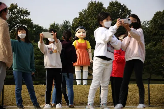 People take a selfie with a giant doll named “Younghee” from Netflix series “Squid Game” on display at a park in Seoul, South Korea, October 26, 2021. “Squid Game” has been watched by 142 million households since its September 17 debut, helping Netflix add 4.38 million new subscribers. (Photo by Kim Hong-Ji/Reuters)