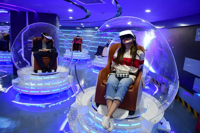 People wearing virtual reality (VR) headsets watch films at a newly opened VR cinema by Er Dong Pictures in Beijing, China on March 27, 2019. (Photo by Lin Hui/Beijing Youth Daily via Reuters)