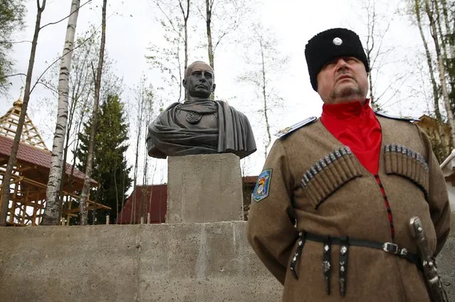 Leader of Orthodox Cossack Union “Irbis” Andrei Polyakov stands next to a bust of Russian President Vladimir Putin which depicts him as a Roman emperor, during its unveiling ceremony in Leningrad region, Russia, May 16, 2015. (Photo by Maxim Zmeyev/Reuters)