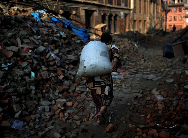 A woman carries a bag as she walks on debris of collapsed houses, in the early morning hours in Bhaktapur near Kathmandu, Nepal, May 14, 2015. (Photo by Ahmad Masood/Reuters)
