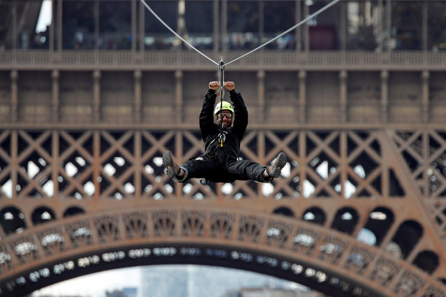 A participant rides a zip line from the second floor of the Eiffel Tower, 115 metres above the ground along an 800-metre long route, as part of the Smash Perrier free event operating until June 2 in Paris, France, May 28, 2019. (Photo by Charles Platiau/Reuters)