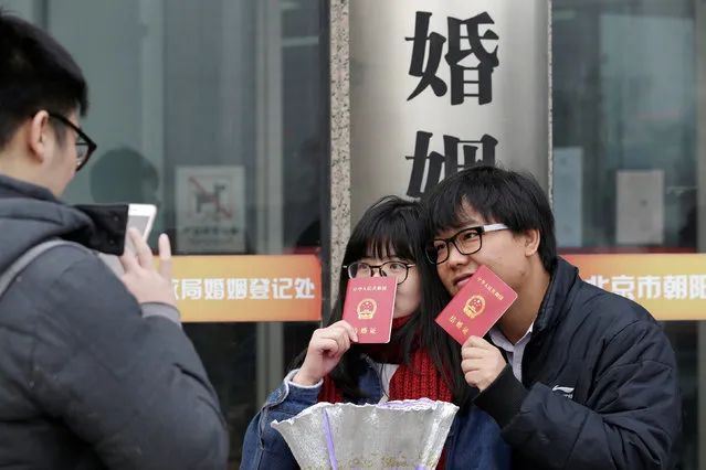 A new couple holding marriage certificates poses for a photo outside a registry office of marriage on Valentine's Day in Beijing, China, February 14, 2017. (Photo by Jason Lee/Reuters)