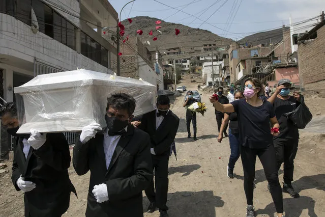Funeral home workers carry the coffin of Pedro Miguel Infante Vilchez, 80, who died from COVID-19, to the “Martires 19 de Julio” cemetery in Comas, on the outskirts of Lima, Peru, Thursday, January 21, 2021. (Photo by Rodrigo Abd/AP Photo)