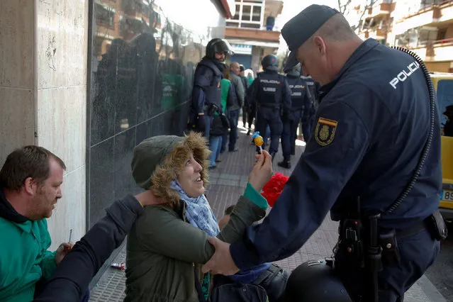 An anti-eviction activist offers a lollipop to a Spanish riot policeman in Parla, Spain March 6, 2017. (Photo by Juan Medina/Reuters)