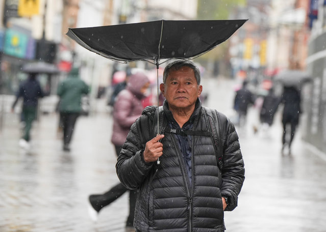A man has his umbrella blown inside out as he braves the rain in Leeds, United Kingdom on April 28, 2024. (Photo by Ioannis Alexopoulos/London News Pictures)