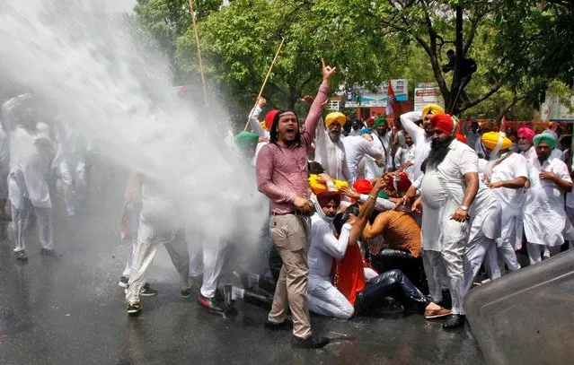 Farmers shout slogans as police use a water cannon to disperse them during a protest in Chandigarh, India, May 4, 2016. Hundreds of farmers on Wednesday held a protest demanding release of payment to the farmers by official agencies that buy wheat for the government, protesting farmers said. (Photo by Ajay Verma/Reuters)