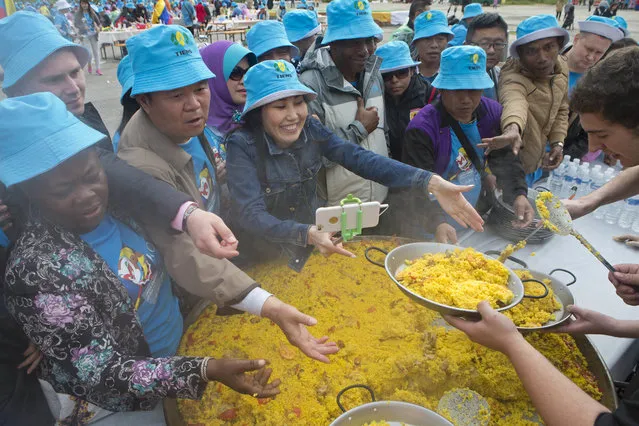 Chinese conglomerate Tiens Group employers are severed Paella in Madrid, Spain, Friday, May 6, 2016. The billionaire founder of Chinese conglomerate Tiens Group is treating 3,000 of his best salespeople to a traditional Spanish paella meal in a free Madrid trip that also includes a bullfight and a tour of King Felipe VI's Royal Palace. The smiling salespeople washed down their heaping plates of paella with sangria Friday at a mass spread of picnic tables in a riverside park during the event footed by Li Jinyuan and organized by China's U Tour travel company. (Photo by Paul White/AP Photo)