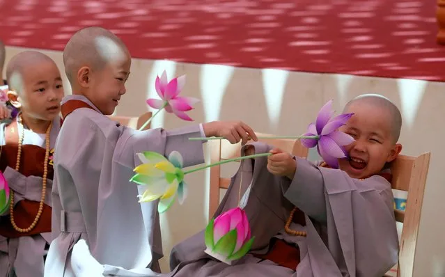 Two children play after having their heads shaved during a service to have an experience of the lives of Buddhist monks for two weeks, at the Jogye Temple in Seoul, South Korea, Wednesday, April 19, 2017. They are two of the eight children who entered the temple to have an experience for two weeks ahead of celebrations for Buddha's upcoming birthday on May 3. (Photo by Lee Jin-man/AP Photo)