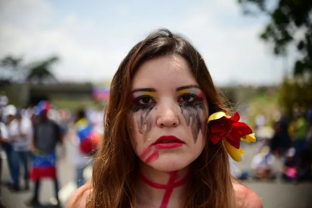 A Venezuelan opposition activist participates in a sit-in to block the Francisco Fajardo motorway in Caracas, on April 24, 2017. Protesters plan Monday to block Venezuela's main roads including the capital's biggest motorway, triggering fears of further violence after three weeks of unrest left 21 people dead. (Photo by Ronaldo Schemidt/AFP Photo)