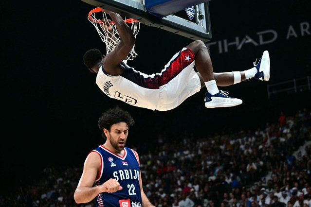 Serbia's guard #22 Vasilije Micic reacts as US guard #05 Anthony Edwards holds onto the basketball rim after scoring during the Basketball Showcase friendly match between the United States and Serbia the at Etihad Arena in Abu Dhabi on July 17, 2024. (Photo by Giuseppe Cacace/AFP Photo)