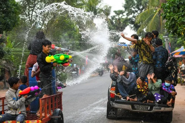 People use water guns to spray water at passengers of a pick-up truck during Khmer New Year celebrations in Siem Reap province on April 15, 2022. (Photo by Tang Chhin Sothy/AFP Photo)