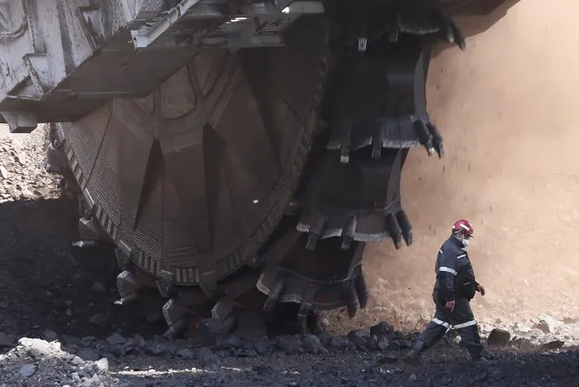 An employee walks past a Soviet-made rotary dredge with the productivity rate of 5,250 tons of processed coal a day during operations at the Beryozovsky opencast colliery, owned by the Siberian Coal Energy Company (SUEK), near the Siberian town of Sharypovo in Krasnoyarsk region, Russia, May 23, 2017. (Photo by Ilya Naymushin/Reuters)