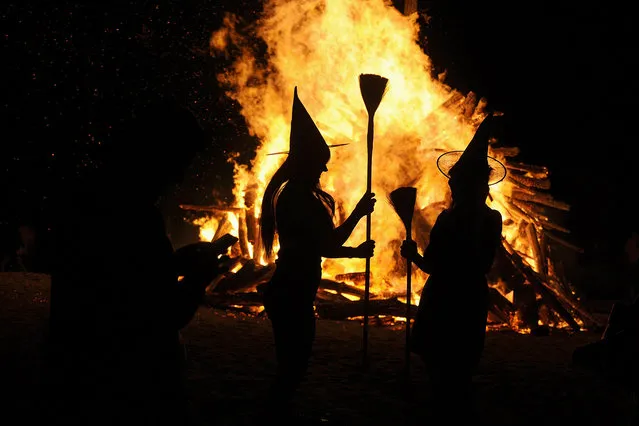 Two women dressed up as witches take pictures in front of the bonfire during the traditional San Juan's (Saint John) night on the beach in Gijon, northern Spain, June 24, 2015. Fires formed by burning unwanted furniture, old school books, wood and effigies of malign spirits are seen across Spain as people celebrate the night of San Juan, a purification ceremony coinciding with the summer solstice. (Photo by Eloy Alonso/Reuters)