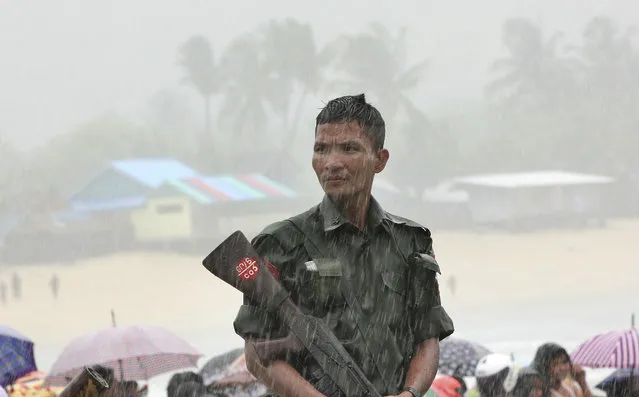 A soldier weathers monsoon rain as bodies are recovered of the waters off San Hlan village, in Laung Lone township, southern Myanmar, Thursday, June 8, 2017. Fishermen have joined navy and air force personnel in recovering bodies and aircraft parts from the sea off Myanmar, where a military plane carrying 122 people including 15 children crashed a day earlier. (Photo by Esther Htusan/AP Photo)