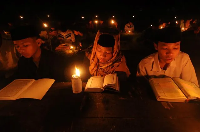 Muslim students illuminated with traditional torches take part in a night reading of Quran to commemorate the Nuzulul Quran, the day of revelation of the holy Quran, at the Nurul Hidayah Al Mubarokah boarding school during the holy fasting month of Ramadan in Boyolali, Central Java province, Indonesia on April 22, 2022. (Photo by Aloysius Jarot Nugroho/Antara Foto via Reuterts)