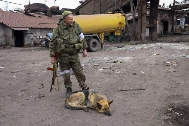 A serviceman stands next to the Illich Iron & Steel Works Metallurgical Plant, the second largest metallurgical enterprise in Ukraine, in an area controlled by Russian-backed separatist forces in Mariupol, Ukraine, Saturday, April 16, 2022. Mariupol, a strategic port on the Sea of Azov, has been besieged by Russian troops and forces from self-proclaimed separatist areas in eastern Ukraine for more than six weeks. (Photo by Alexei Alexandrov/AP Photo)