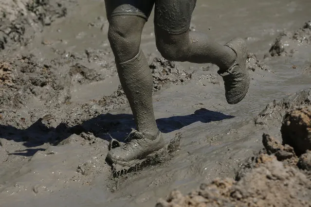 A participant runs in the mud during the Mud Day athletic event at El Goloso Military base on the outskirts of Madrid, Spain, Saturday, June 11, 2016. (Photo by Paul White/AP Photo)