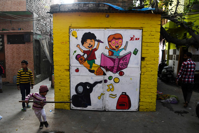 Children play near a mural painted by artists from “Delhi Street Art” group at the Raghubir Nagar slum in New Delhi on December 2, 2019. (Photo by Sajjad Hussain/AFP Photo)