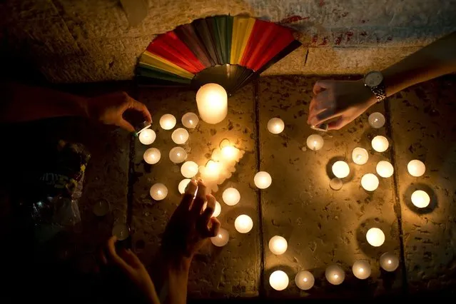 Members LGBT community light candles in solidarity with Florida's shooting attack victims, in Tel Aviv, Israel, Sunday, June 12, 2016. The shooting attack in Orlando, Florida, USA, Sunday, left more than 50 people dead amid a multitude of events celebrating LGBT Pride Month. (Photo by Oded Balilty/AP Photo)